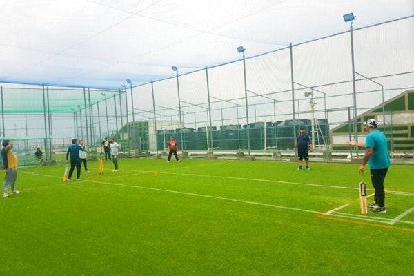 A group playing box cricket on the turf
